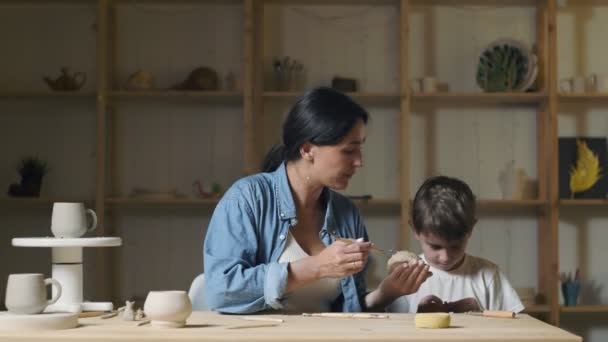 Petit garçon et femme professeur joue avec l'argile en classe de poterie — Video