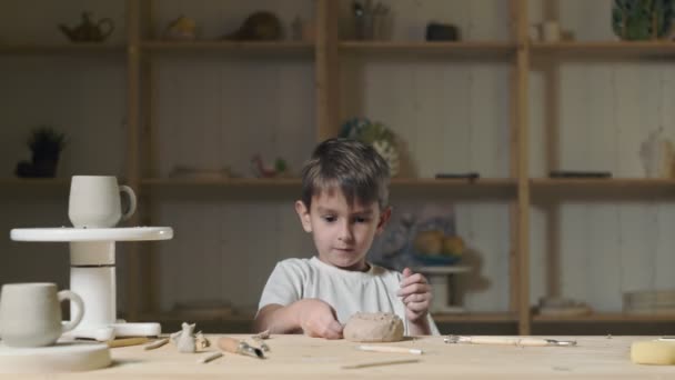 Petit garçon joue avec l'argile en classe de poterie — Video