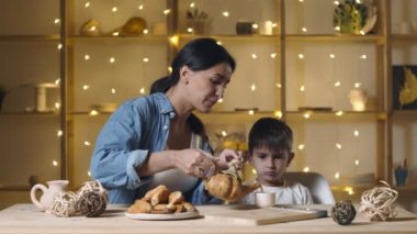Anne ve oğul çay içip çörek ve kruvasan yiyorlar.