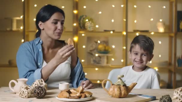 Feliz madre e hijo bebiendo té y comiendo bollos y croissant — Vídeo de stock