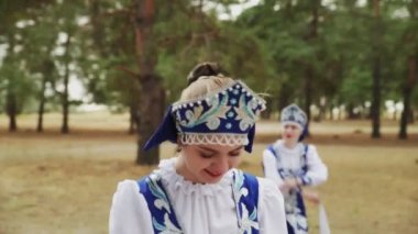 Mavi Rus Geleneksel Halk Kostümleri içinde genç ve güzel bir kadın yaz ormanında dans ediyor.