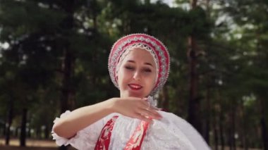 Genç bir kadın yaz ormanlarında geleneksel Rus danslarıyla dans ediyor.