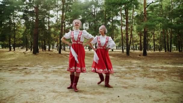 Zwei junge und schöne Frauen tanzen russische traditionelle Tänze im Sommerwald — Stockvideo