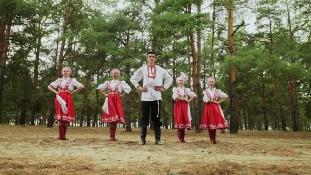 Um homem e quatro mulheres jovens estão dançando russo danças tradicionais na floresta de verão — Vídeo de Stock