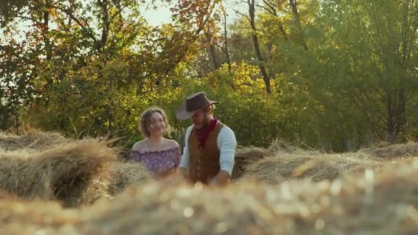 Молодой ковбой и его девушка ходят по сену на ферме — стоковое видео