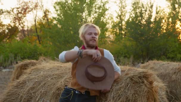 Vaquero guapo posando cerca del heno en su granja — Vídeos de Stock