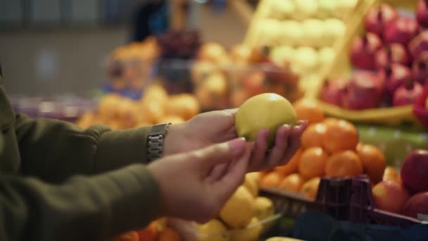 Close-up van de vrouw kiest citroenen in de winkel planken op de markt — Stockvideo