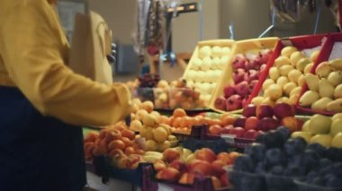 Bir adam taze bir mandalina seçer ve onları markette bir kese kağıdına koyar.