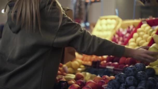 Jonge vrouw stopt peren in een papieren zak op de markt — Stockvideo