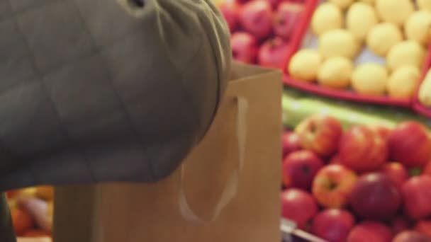 Gros plan de la femme met des pommes rouges dans un sac en papier au marché — Video