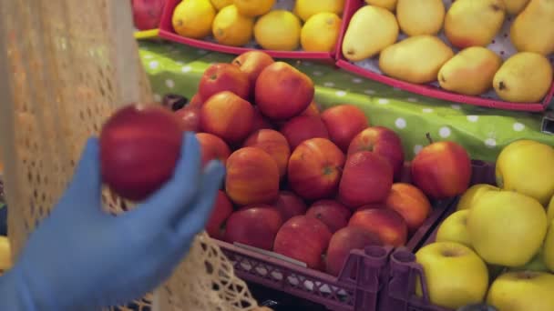 Primo piano della donna in cappotto giallo mette mele rosse in borsa stringa al mercato — Video Stock