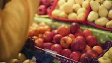 Erkek, marketten taze kırmızı elma seçer.