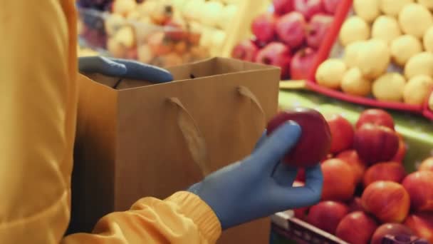 Primo piano dell'uomo mette le mele rosse in un sacchetto di carta al mercato — Video Stock