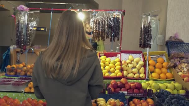 Achteraanzicht van jonge vrouw geeft een papieren zak aan verkoper op de markt — Stockvideo