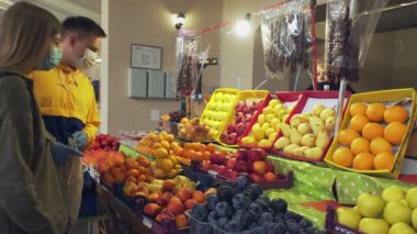 Genç çift koruyucu maskeler ve eldivenler marketten meyve seçiyor.