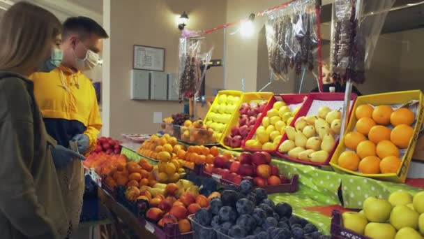 Jonge paar beschermende maskers en handschoenen kiest vruchten op de markt — Stockvideo