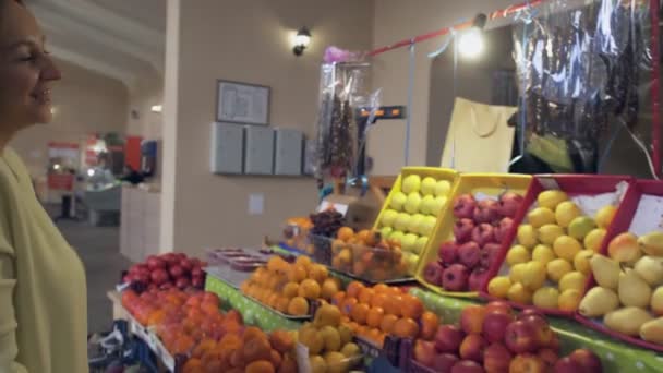 Mujer con abrigo amarillo toma una bolsa de papel del vendedor en el mercado — Vídeos de Stock