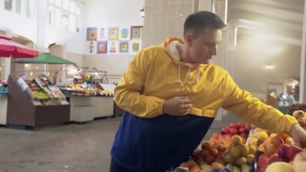 Νεαρός άνδρας μυρίζει και επιλέγει ένα φρέσκο μήλο στην αγορά — Αρχείο Βίντεο