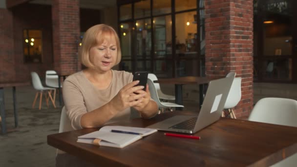 Mulher sênior positivo ter uma chamada de vídeo no café — Vídeo de Stock