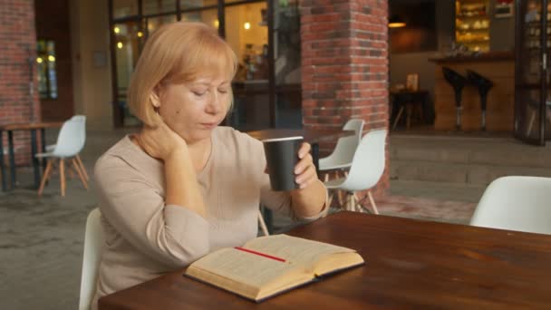 Γυναίκα συγγραφέας βιβλίων πίνει καφέ και γράφει βιβλίο στο καφέ — Αρχείο Βίντεο