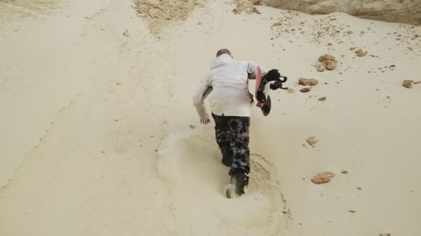 Πίσω όψη ενός όμορφου άντρα που σκαρφαλώνει σε ένα βουνό με άμμο στην έρημο ή σε λατομείο άμμου — Αρχείο Βίντεο