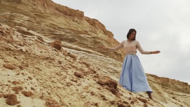 Beautiful and dreamy young woman dances on a background of mountains — Stock Video