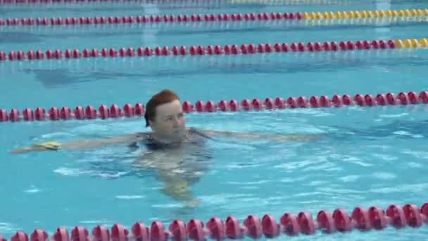 Старушка тренирует аква-гимнастику в бассейне. — стоковое видео
