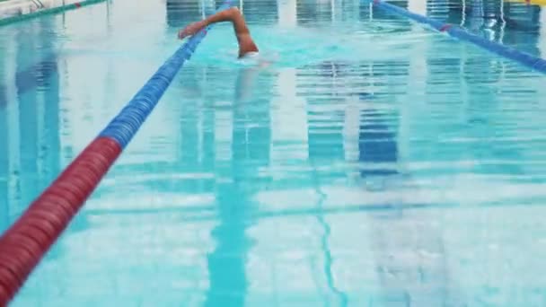 Professionele zwemmer nauwelijks uit te werken in het overdekte zwembad zwemmen over de baan. — Stockvideo