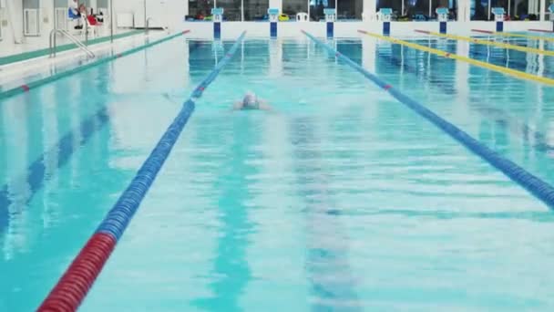 Nadador profissional mal trabalhando na piscina interior nadando através da pista. — Vídeo de Stock