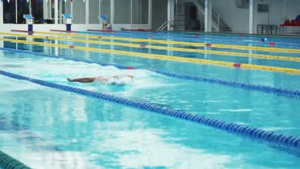 Nadador mal trabalhando na piscina interior nadando através da pista. — Vídeo de Stock