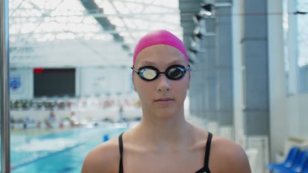 Joven atleta nadadora con gafas y sombrero mira a la cámara — Vídeos de Stock