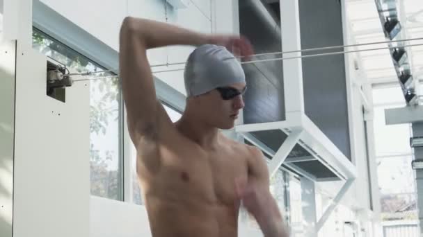 Vista laterale del bel nuotatore atleta riscalda il suo corpo prima di nuotare — Video Stock