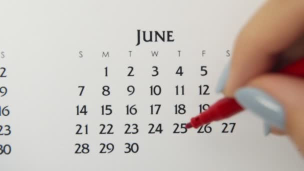 赤いマーカーでカレンダー日付の女性の手の円の日。ビジネスの基本壁カレンダープランナーと主催者。6月25日 — ストック動画