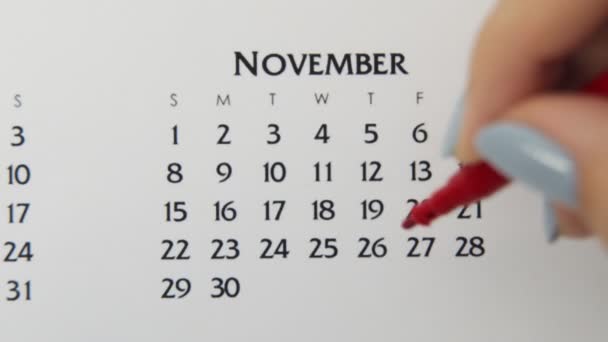 赤いマーカーでカレンダー日付の女性の手の円の日。ビジネスの基本壁カレンダープランナーと主催者。11月26日 — ストック動画