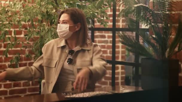 Mladé dvě ženy s ochrannými maskami se setkávají v kavárně u okna — Stock video