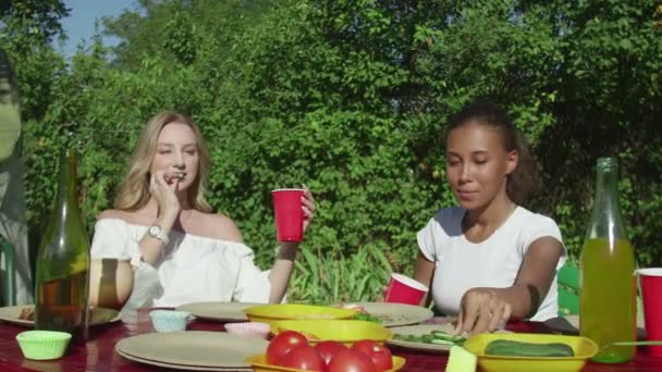 Young women sits at the table, eats vegetables, drinks and waits for bbq — Stock Video