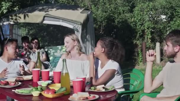 Zahradní slavnost, Shromáždili se u stolu Přátelé. Lidé pijí, předávají jídla, vtipkují a baví se. — Stock video