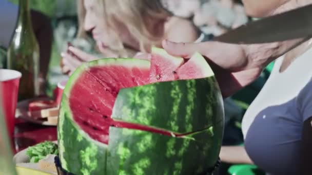 Männliche Hand hält Messer und schneidet saftige Wassermelone beim Picknick im Freien. — Stockvideo