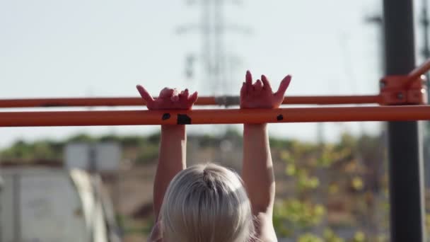 Une jeune athlète féminine se hisse sur la barre horizontale. En plein air. Séance d'entraînement — Video