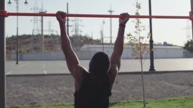 Afrikalı bir adamın yatay antremanda barfiks çekerken görüntüsü.