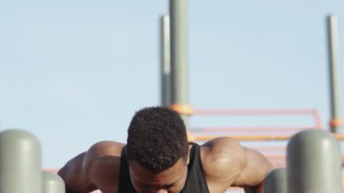 Genç Afrikalı adam şehir parkındaki yatay bara yanaşıyor..