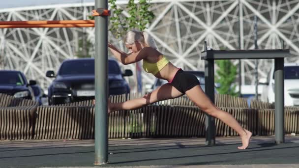 Side view of athletic woman is stretches and sits on the twine — Stock Footage Side view of athletic woman is stretches and sits on the twine Stock Footage