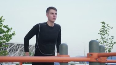 Sporcu sporcunun kapanışı, şehir parkında antrenman yaparken yatay çubuğa yanaşıyor.