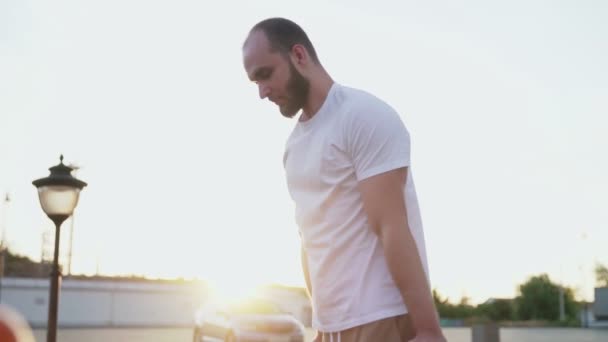 Side view of young man in white t-shirt is pulling up on horizontal bar while training in city park. — Stock Footage Side view of young man in white t-shirt is pulling up on horizontal bar while training in city park. Video Clip