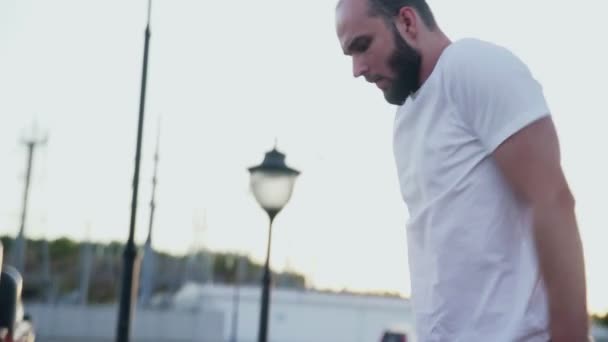 Side view of young man in white t-shirt is pulling up on horizontal bar while training in city park. — Stock Footage Side view of young man in white t-shirt is pulling up on horizontal bar while training in city park. Royalty Free Stock Video