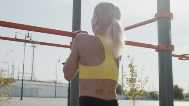 젊은 여성 운동 선수가 수평봉을 타고 옵니다. 옥외에서. 구직 활동 — 비디오