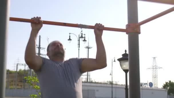 Hombre deportivo senior haciendo flexiones en el entrenamiento horizontal al aire libre — Vídeos de Stock