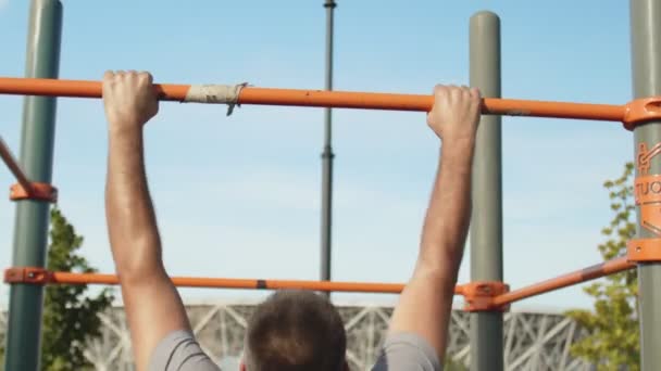Rückenansicht eines älteren sportlichen Mannes, der Klimmzüge beim horizontalen Training im Freien macht — Stockvideo
