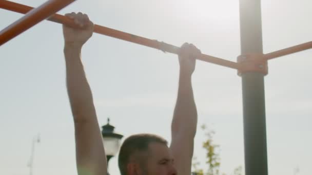 Senior sporty man hangs on a horizontal bar and lifts up his legs — Stock Footage Senior sporty man hangs on a horizontal bar and lifts up his legs Royalty Free Stock Footage