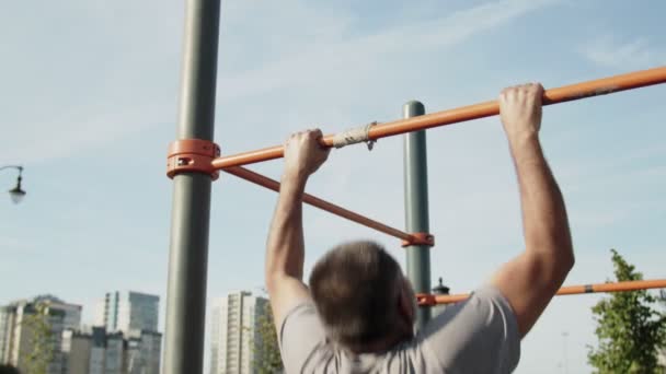 Senior homme faisant pull ups sur l'entraînement horizontal à l'extérieur — Video